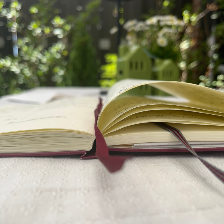 Geöffnetes Notizbuch für Trauergespräch mit verschwommenem Hintergrund in einem grünen Garten.